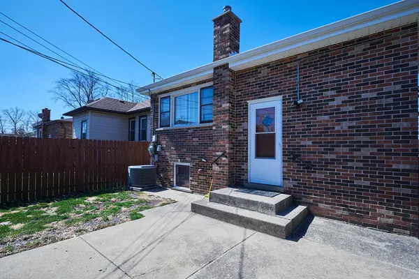 a brick house with a small yard and wooden fence