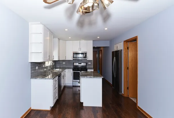 a kitchen with stainless steel appliances granite countertop a refrigerator a stove top oven a sink and dishwasher