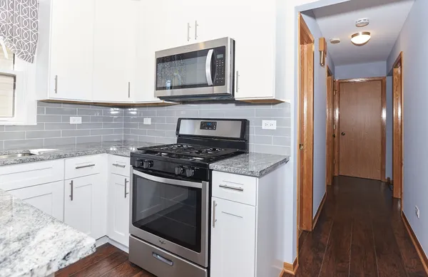 a kitchen with granite countertop cabinets stainless steel appliances and wooden floor