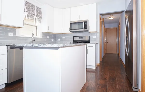 a kitchen with kitchen island granite countertop a sink and wooden cabinets