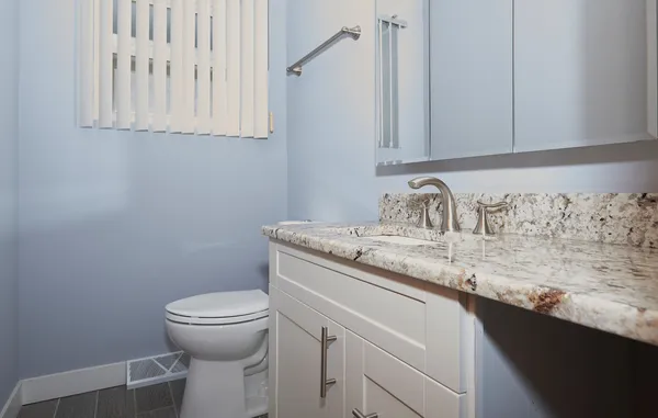 a bathroom with a granite countertop sink and a toilet