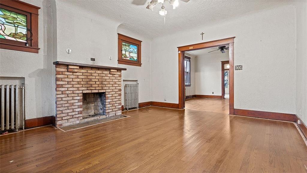 315 Catherine Street McKees Rocks, PA 15136 - Photo 7 of 38 an empty room with wooden floor a fireplace and windows