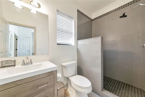 a bathroom with a granite countertop sink a toilet and a mirror
