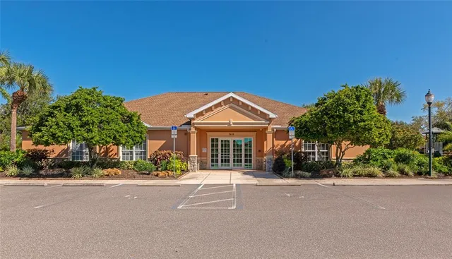 a view of a stone house with a big yard and large tree