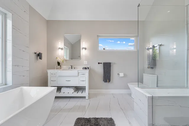a spacious bathroom with a tub sink and mirror