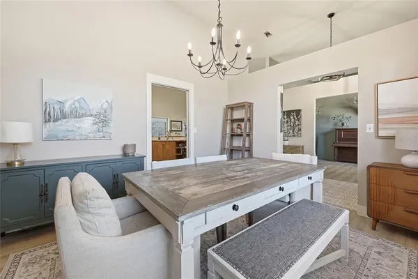 a dining room with wooden floor a chandelier a wooden table and chairs