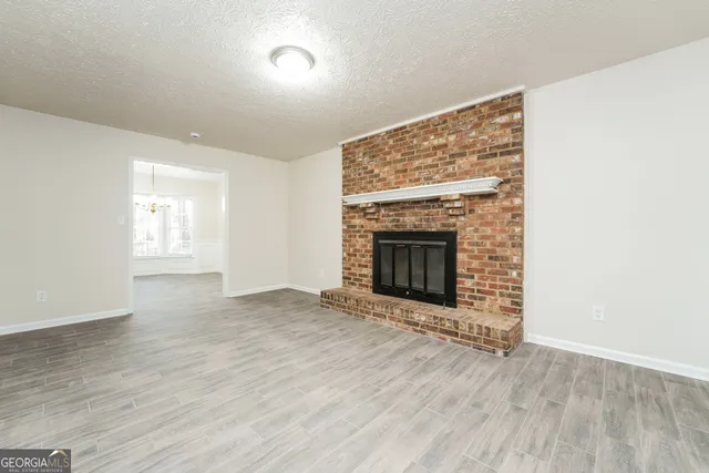 an empty room with wooden floor fireplace and windows