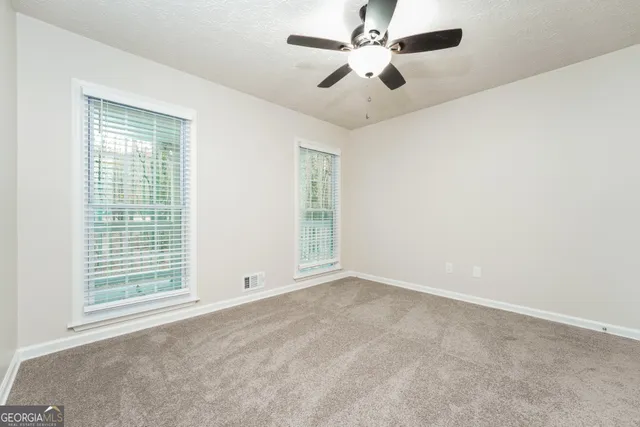 an empty room with windows and fan