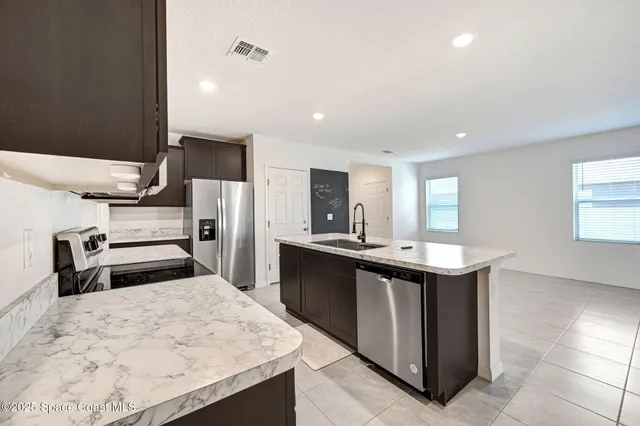 a kitchen with stainless steel appliances kitchen island sink refrigerator and stove
