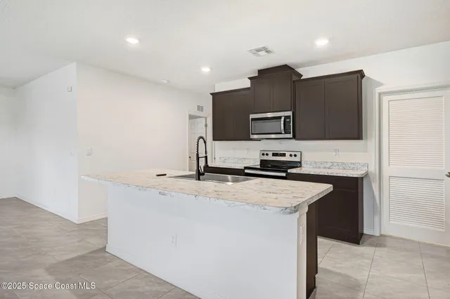 a kitchen with stainless steel appliances a stove top oven a sink and a refrigerator