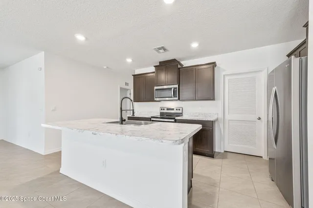 a kitchen with stainless steel appliances granite countertop a sink and a refrigerator