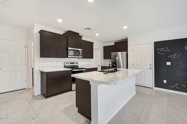 a large kitchen with stainless steel appliances granite countertop a stove a sink a refrigerator and a microwave