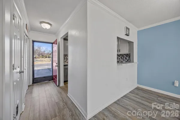 a view of a hallway with wooden floor and a bathroom