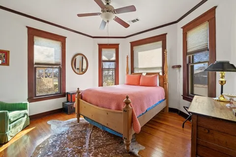 a bedroom with a bed a dresser and windows