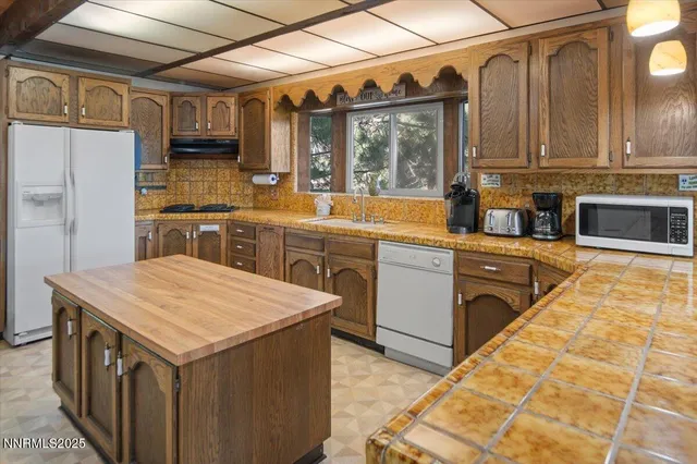 a kitchen with stainless steel appliances granite countertop a refrigerator a stove and a sink