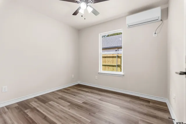 an empty room with a window and ceiling fan