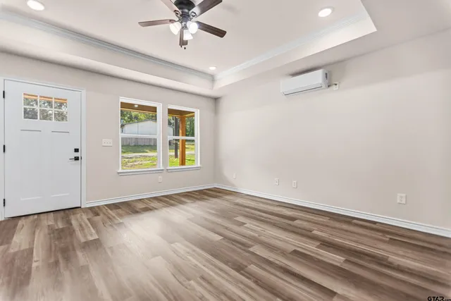 a view of an empty room with a window and wooden floor