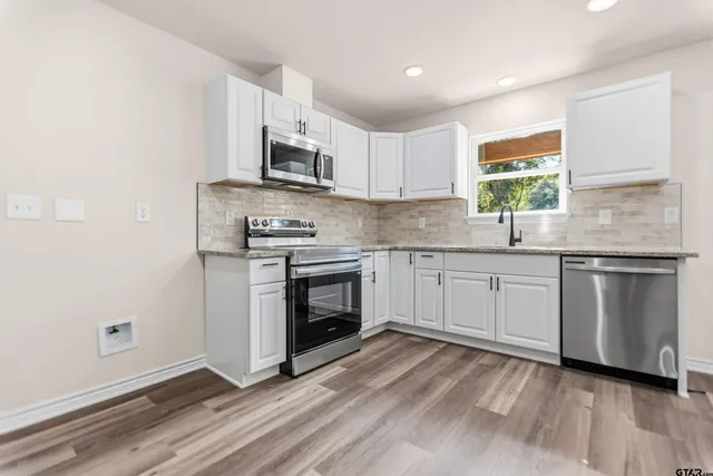 a kitchen with stainless steel appliances a white stove top oven sink and window