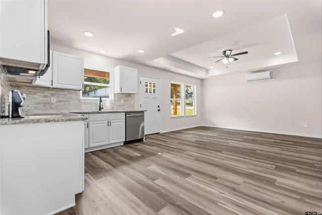a view of a kitchen with a sink and dishwasher with wooden floor