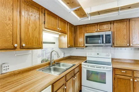 a kitchen with granite countertop a sink stainless steel appliances and cabinets