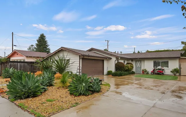 a front view of a house with a yard and potted plants
