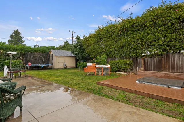 a backyard of a house with table and chairs plants and large tree