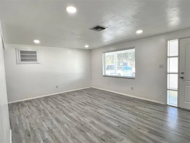 an empty room with wooden floor and windows