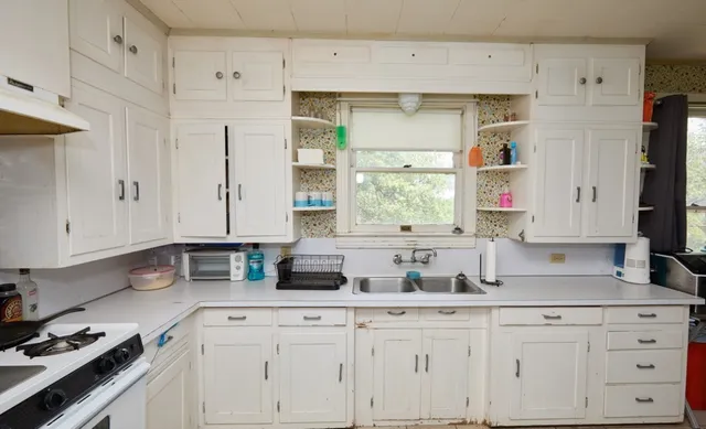 a kitchen with granite countertop white cabinets white appliances and sink