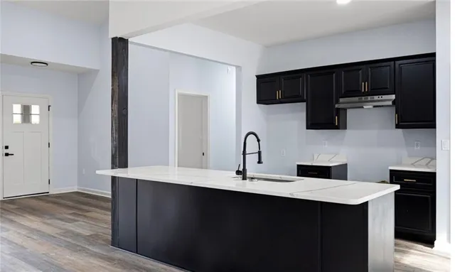 a kitchen with stainless steel appliances a sink dishwasher a microwave oven and a stove with wooden floor