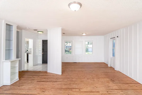 a view of an empty room with wooden floor and a bathroom