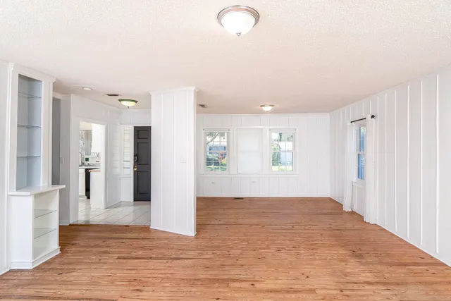 a view of an empty room with wooden floor and a bathroom