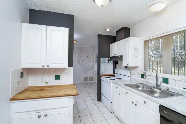 a kitchen with granite countertop a sink stove and white cabinets