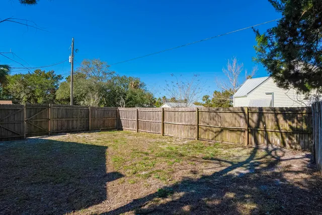 a view of a backyard with wooden fence and a large tree