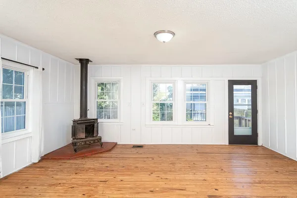 a view of an empty room with a window and wooden floor