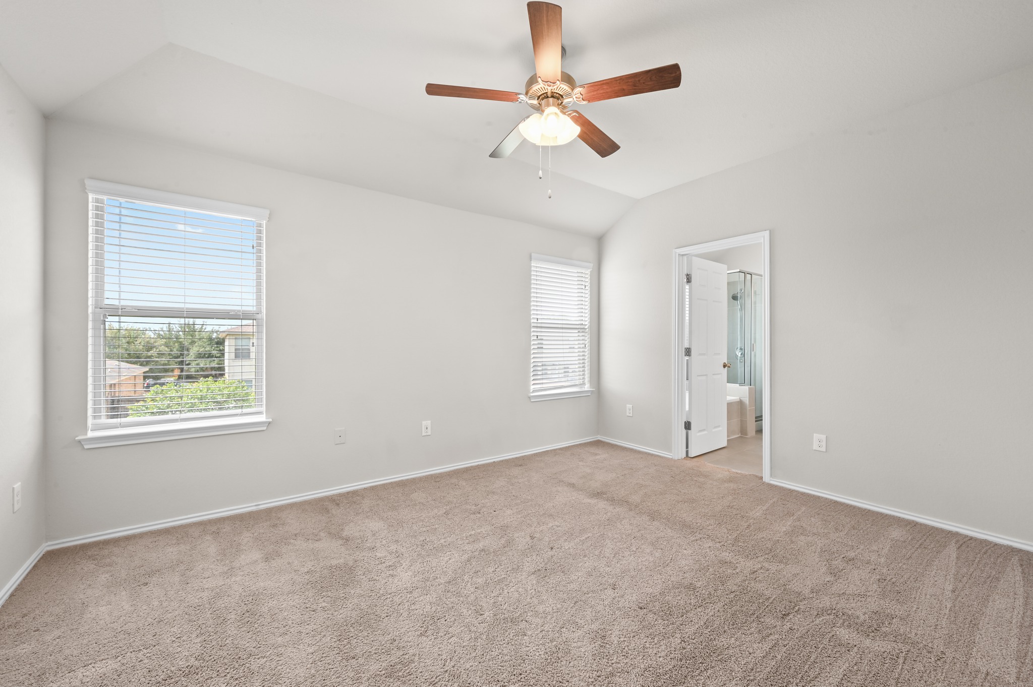 209 Noddy Road Buda, TX 78610 - Photo 17 of 30 Spacious room featuring vaulted ceilings, two windows with blinds, plush carpet flooring, and a ceiling fan with light fixture