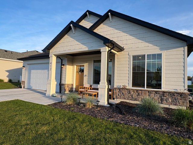 412 West 3025th Street South Logan, UT 84321 - Photo 5 of 34 Craftsman house featuring a porch, driveway, stone siding, an attached garage, and a front lawn