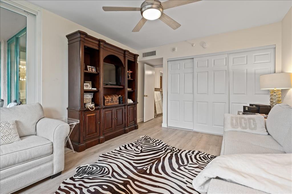 100 Southeast 5th Avenue, Unit 412 Boca Raton, FL 33432 - Photo 33 of 62 a spacious bedroom with a bed a couch and a bookshelf with wooden floor