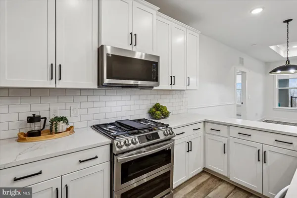 a kitchen with white cabinets stainless steel appliances and a counter space