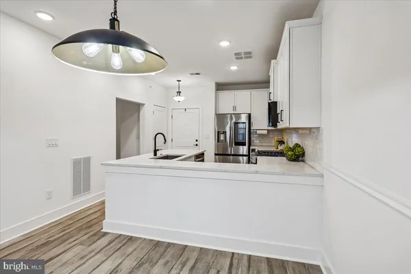 a kitchen with stainless steel appliances a sink cabinets and wooden floor