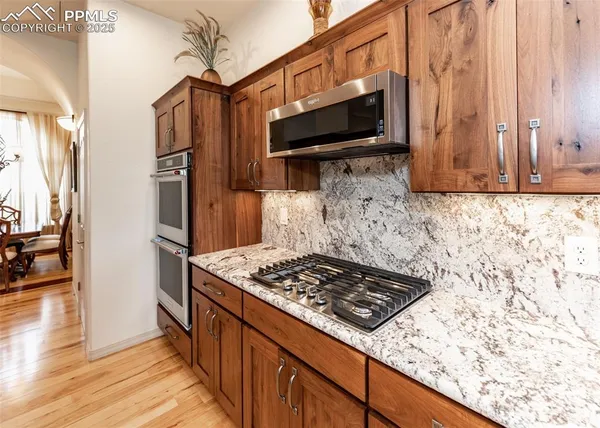 a kitchen with stainless steel appliances granite countertop a stove and a wooden cabinets