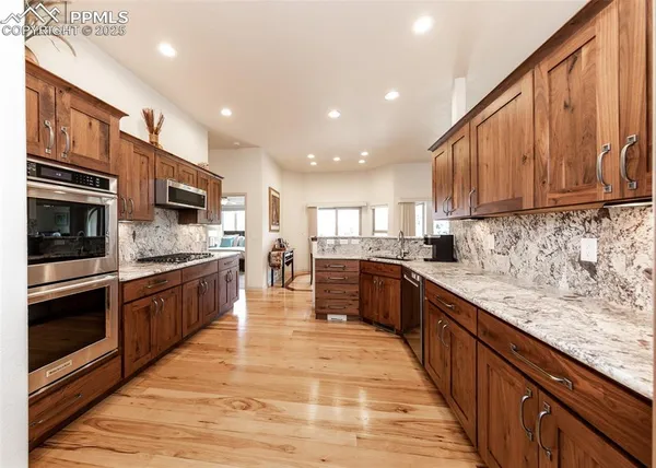 a large kitchen with stainless steel appliances wooden cabinets and a stove top oven