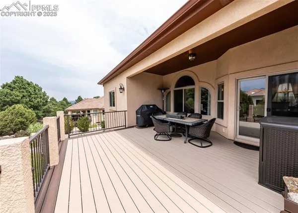 a view of a roof deck with table and chairs a barbeque with wooden floor and fence