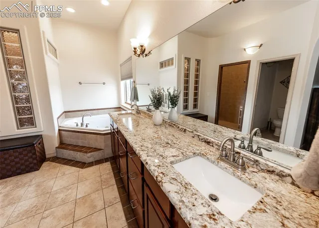 a bathroom with a granite countertop sink a mirror and a bathtub