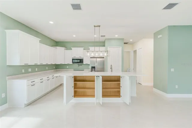 a large white kitchen with granite countertop a white stove top oven and white cabinets