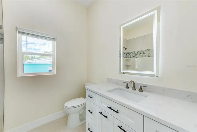 a bathroom with a granite countertop sink a toilet and a window
