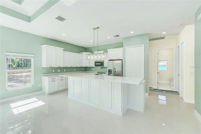 a kitchen with white cabinets and window
