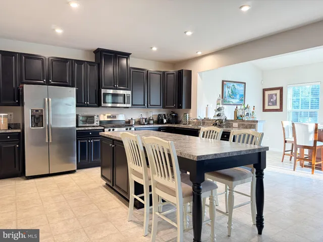 a kitchen with stainless steel appliances granite countertop a refrigerator a stove a sink a dining table and chairs