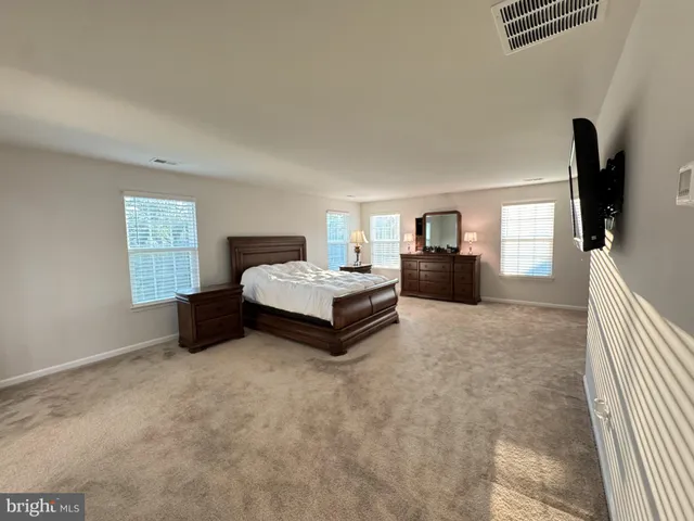 a spacious bedroom with a bed and a flat screen television
