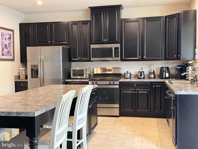 a kitchen with granite countertop wooden cabinets a refrigerator and a sink