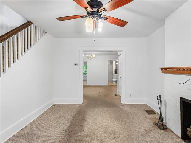 an empty room with a fireplace and chandelier fan